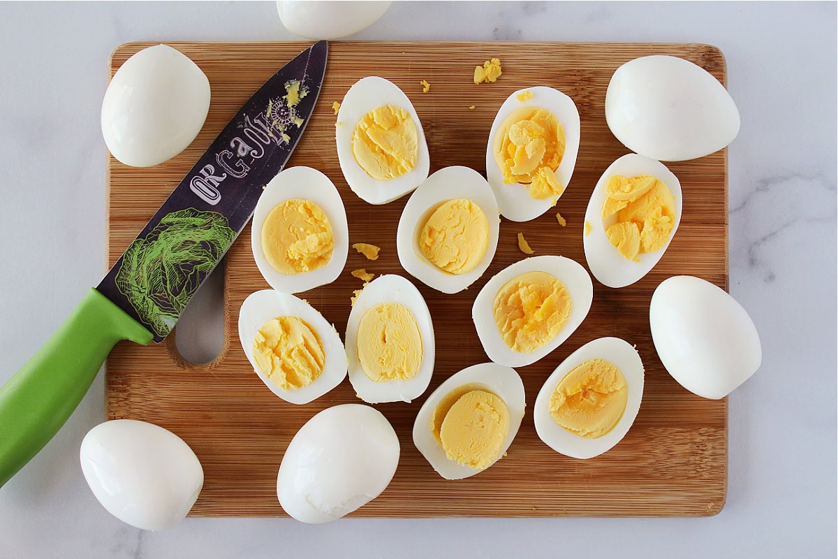 Hard boiled eggs cut in half on a wooden cutting board.