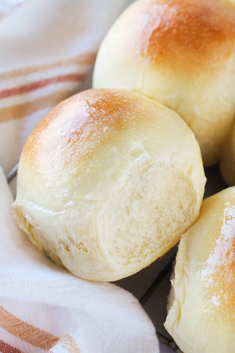Golden brown sourdough rolls in a towel-lined basket.