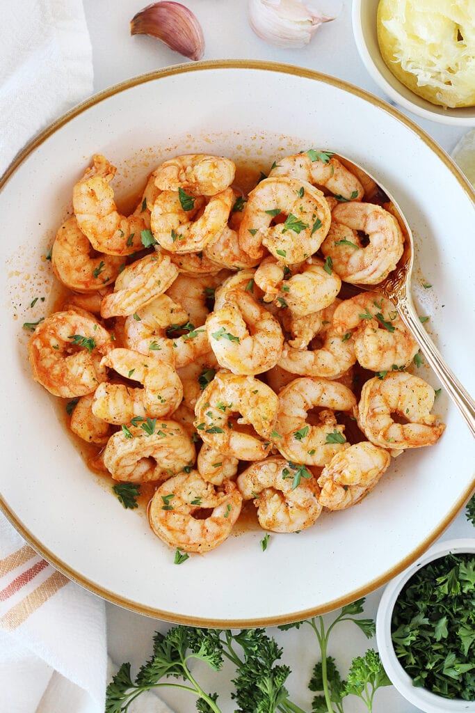 Baked shrimp seasoned with paprika and lemon juice in a white bowl.
