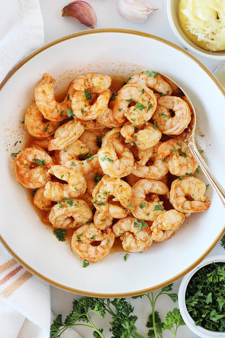 Baked shrimp seasoned with paprika and lemon juice in a white bowl.