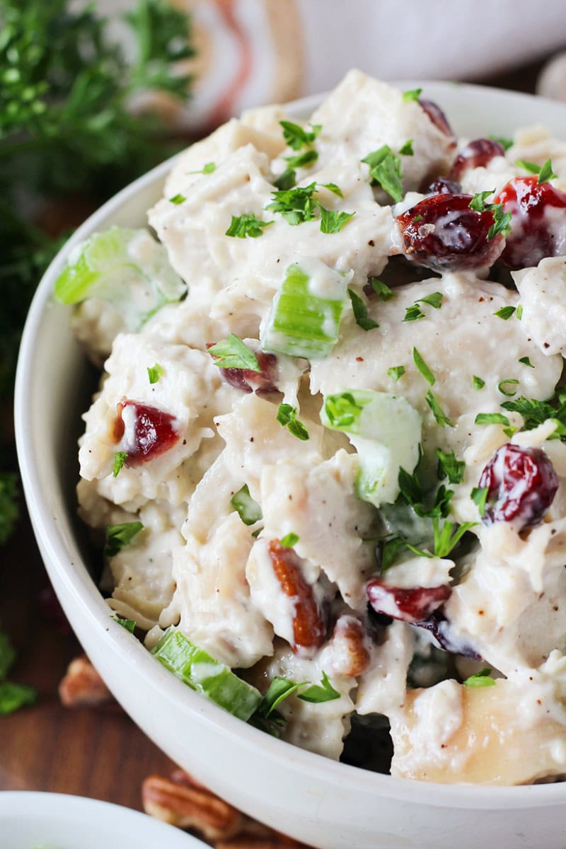Chopped celery, halved pecans, and dried cranberries in creamy chicken salad with mayo.