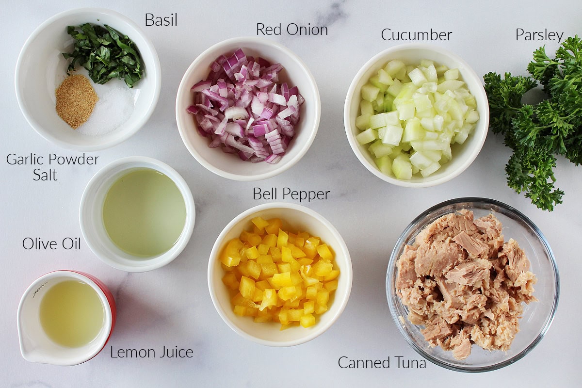 Labeled ingredients for Mediterranean Tuna Salad on a white marble countertop.