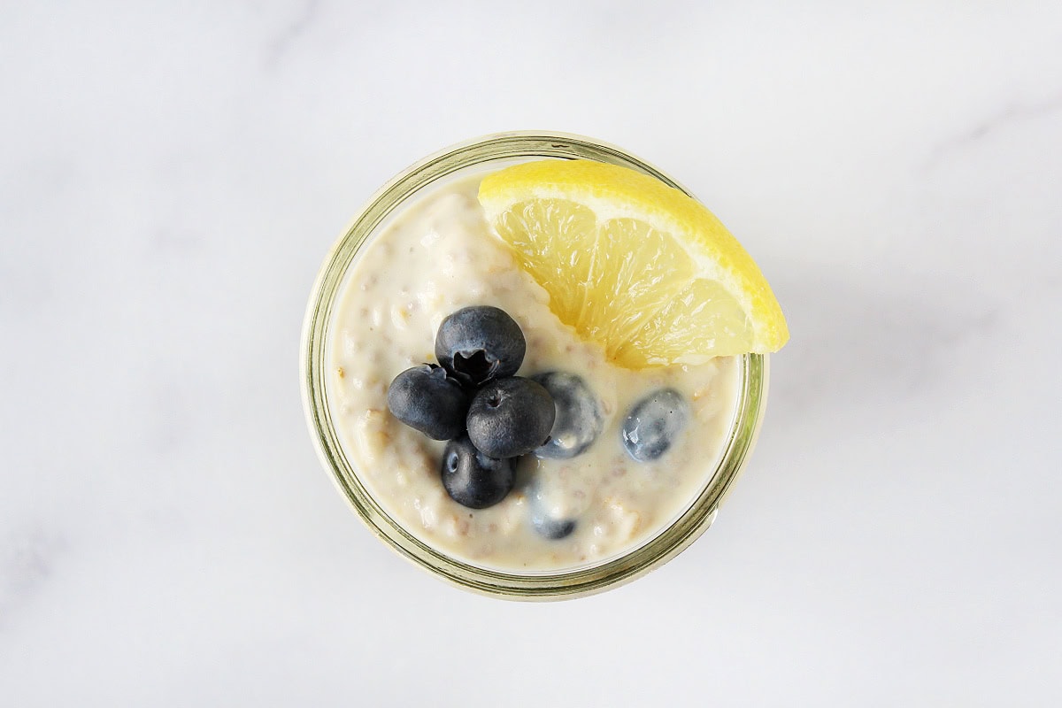 Lemon wedge and fresh blueberries on top of overnight oats jar.