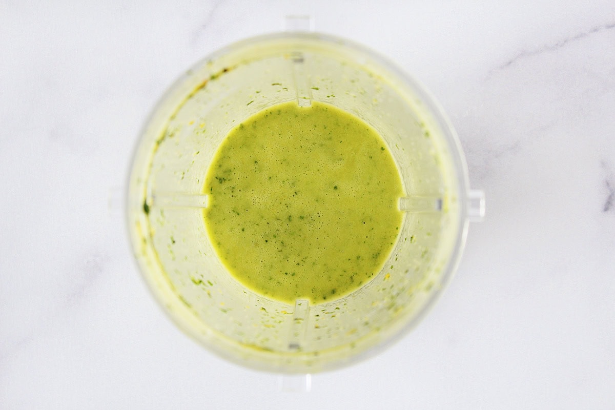 Blended mint and basil citrus dressing in a blender jar.