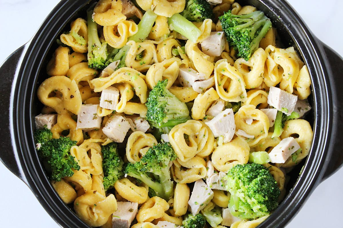 Chicken tortellini with broccoli in a black pot.