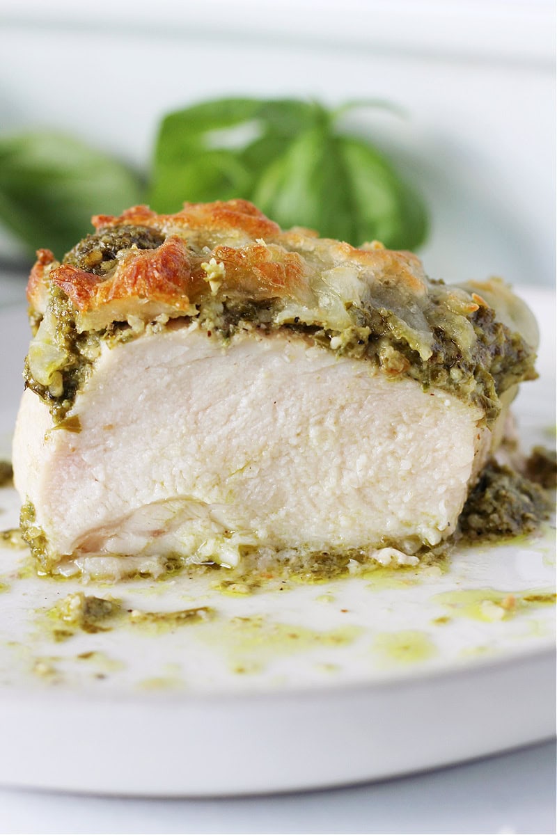 A baked pesto chicken breast cut in half on a white plate.